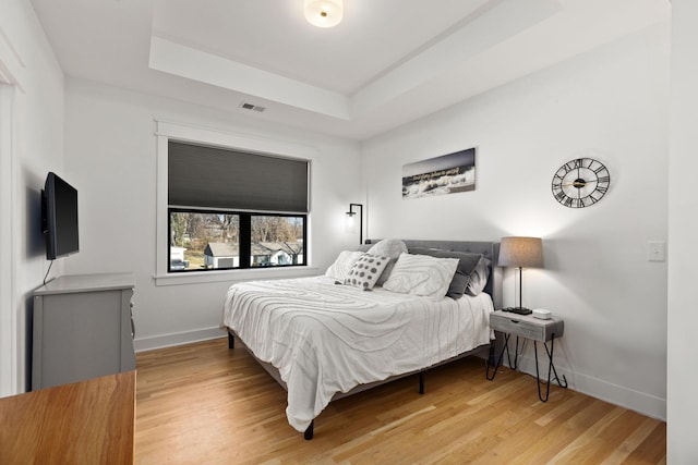 bedroom with a tray ceiling and hardwood / wood-style flooring