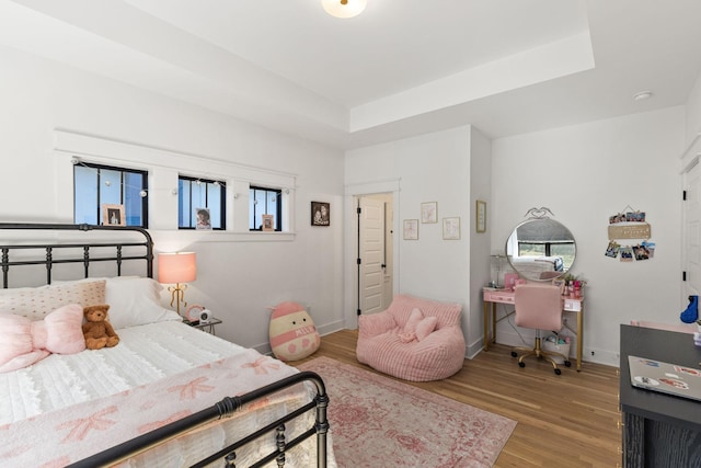 bedroom with a tray ceiling and hardwood / wood-style flooring