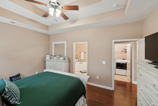 bedroom with washer / clothes dryer, a tray ceiling, ceiling fan, and hardwood / wood-style flooring