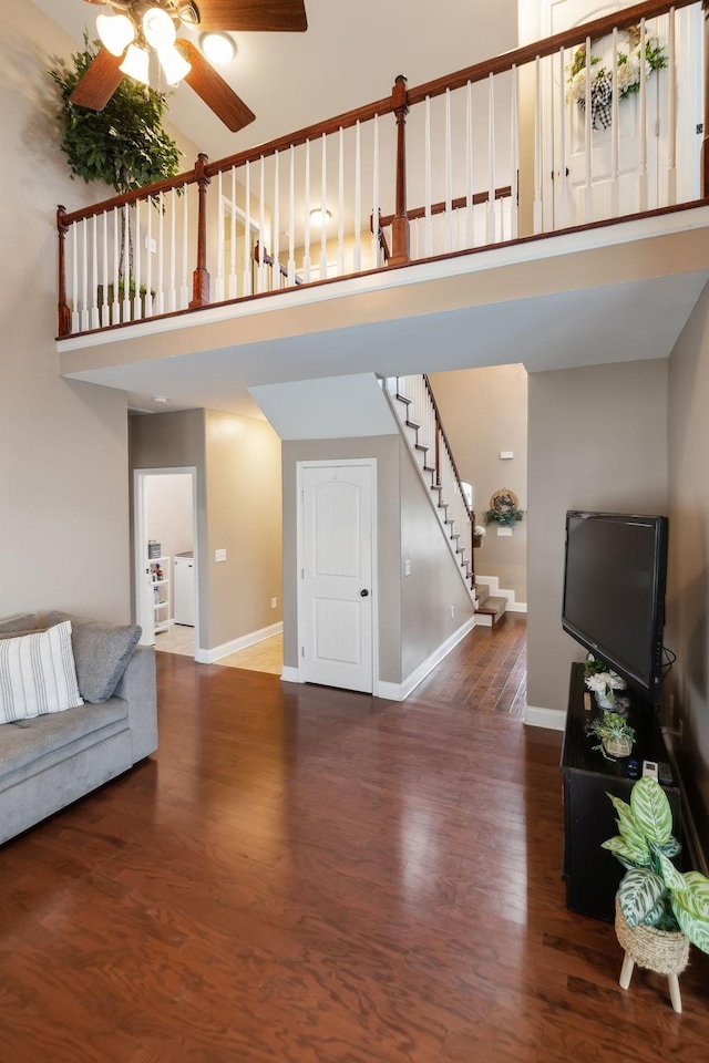 living room with a high ceiling, dark wood-type flooring, washing machine and clothes dryer, and ceiling fan