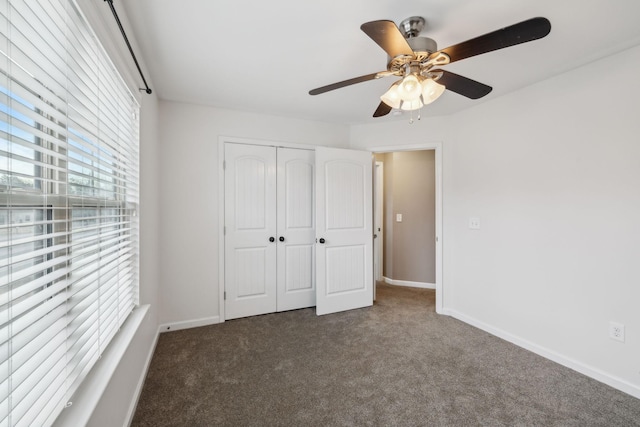 unfurnished bedroom with dark carpet, a closet, and ceiling fan