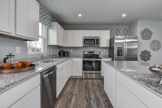 kitchen featuring sink, dark hardwood / wood-style floors, stainless steel appliances, light stone countertops, and white cabinets