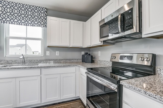 kitchen with sink, stainless steel appliances, dark hardwood / wood-style floors, light stone counters, and white cabinets