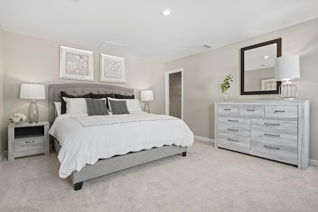 bedroom with light carpet, a walk in closet, and a closet