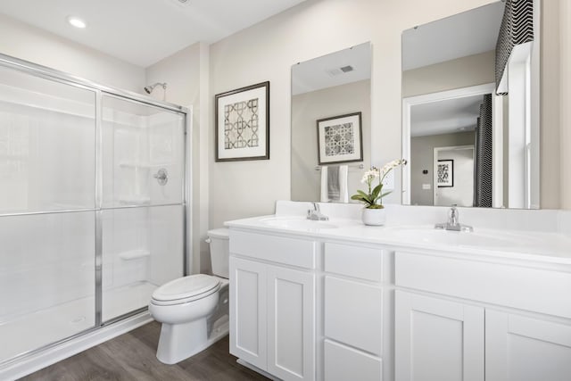 bathroom with hardwood / wood-style flooring, vanity, an enclosed shower, and toilet