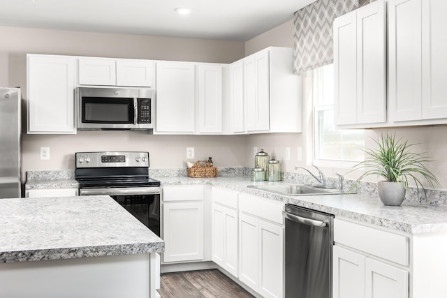 kitchen with dark wood-type flooring, stainless steel appliances, sink, and white cabinets