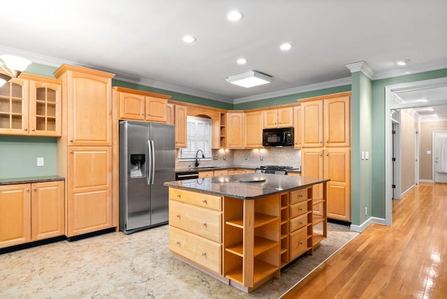 kitchen with sink, crown molding, dark stone countertops, stainless steel fridge, and a kitchen island