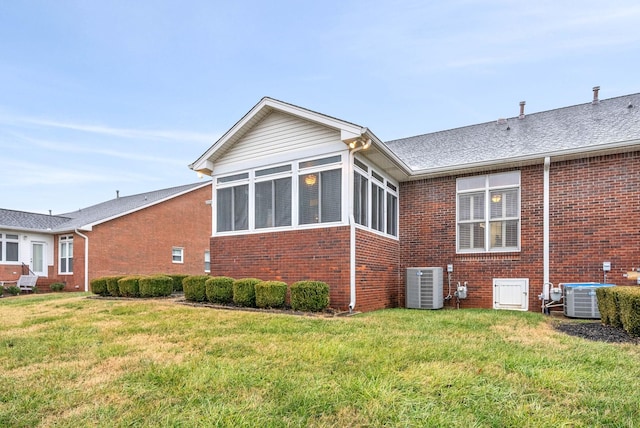 view of side of home with central AC, a lawn, and a sunroom