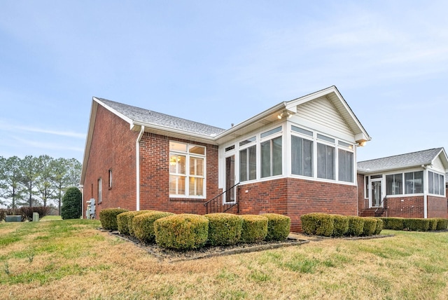 view of side of home featuring a sunroom and a lawn