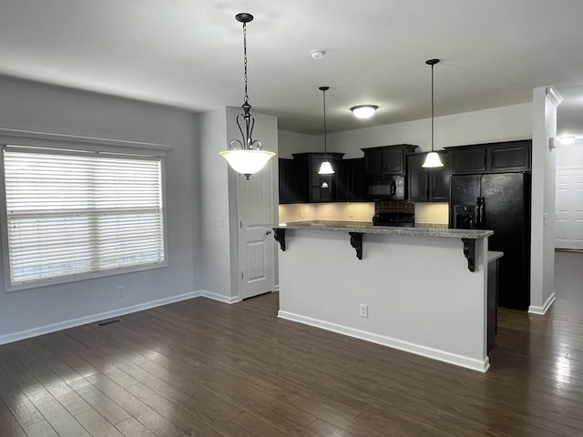 kitchen with hanging light fixtures, a kitchen breakfast bar, dark hardwood / wood-style flooring, a kitchen island, and black appliances