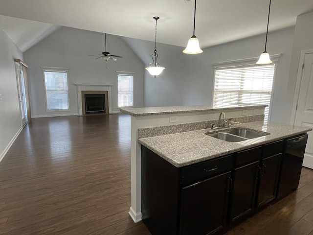 kitchen featuring dark wood-type flooring, sink, vaulted ceiling, an island with sink, and pendant lighting