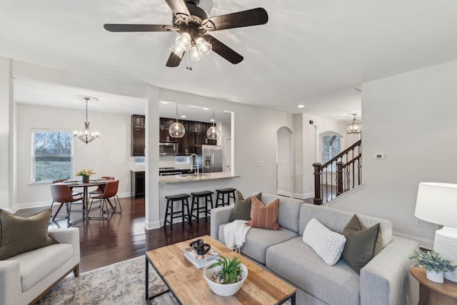 living room featuring dark wood-type flooring and ceiling fan with notable chandelier