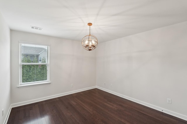 empty room with dark wood-type flooring and a chandelier