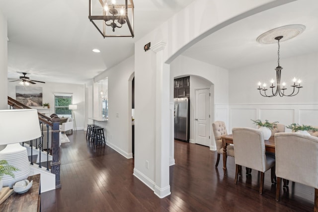 dining area featuring ceiling fan with notable chandelier and dark wood-type flooring