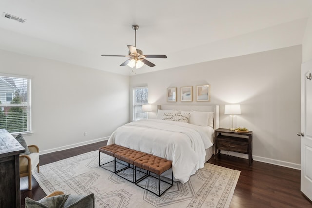 bedroom with ceiling fan, dark hardwood / wood-style flooring, and multiple windows