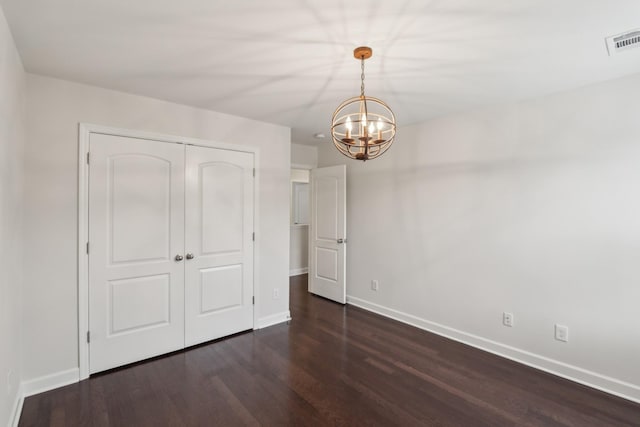 unfurnished bedroom with dark hardwood / wood-style floors, a chandelier, and a closet