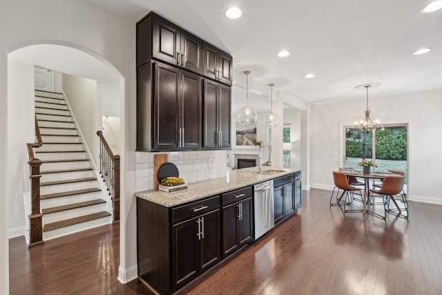 kitchen featuring pendant lighting, dishwasher, sink, backsplash, and light stone counters