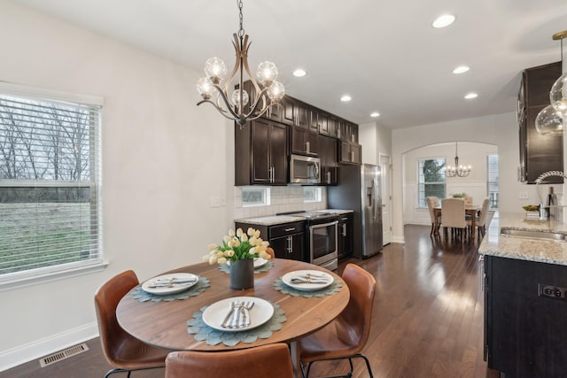 dining space with a notable chandelier, dark wood-type flooring, and sink