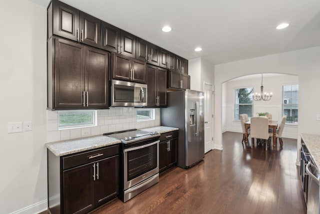 kitchen featuring appliances with stainless steel finishes, dark hardwood / wood-style floors, dark brown cabinetry, and decorative light fixtures