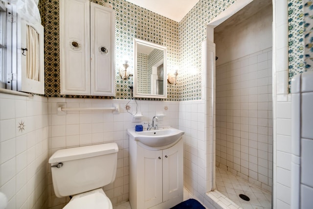 bathroom featuring vanity, tile walls, toilet, and tiled shower