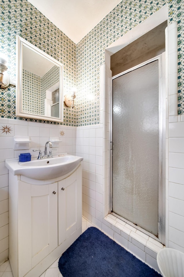 bathroom featuring walk in shower, vanity, and tile walls