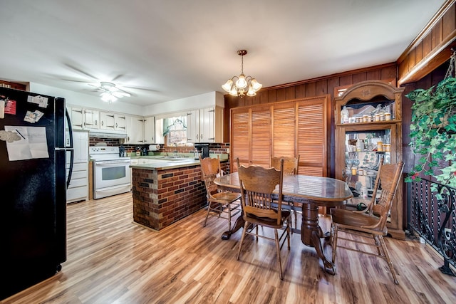 dining space featuring ceiling fan with notable chandelier and light hardwood / wood-style flooring