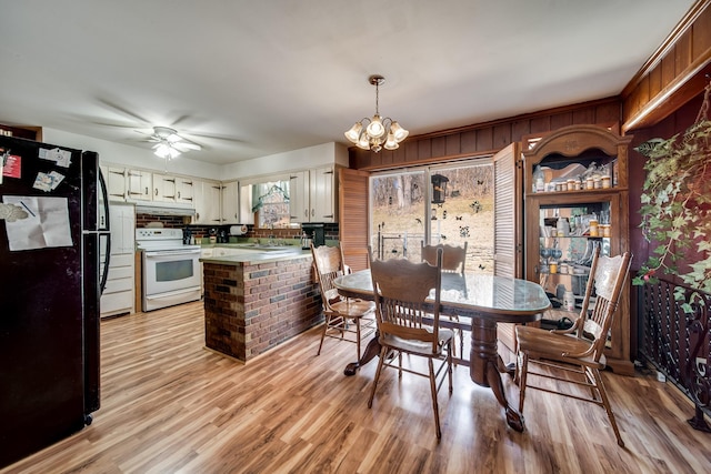 dining room with ceiling fan with notable chandelier and light hardwood / wood-style floors