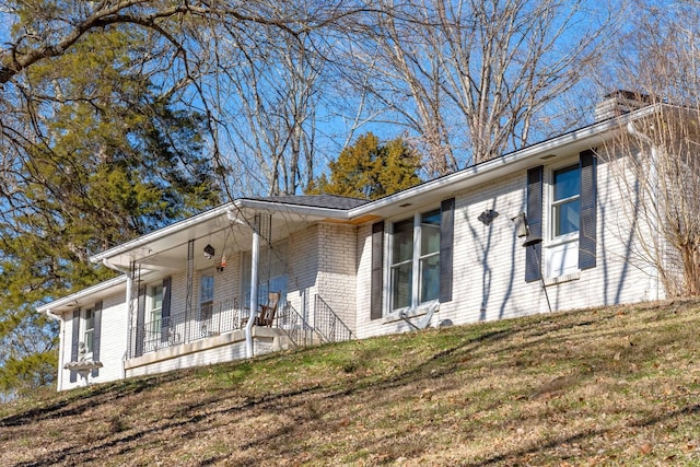 view of side of home featuring a porch and a yard