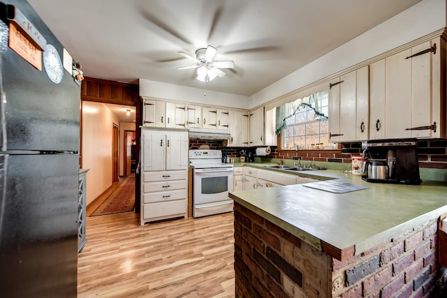 kitchen featuring sink, ceiling fan, white range with electric stovetop, black fridge, and kitchen peninsula