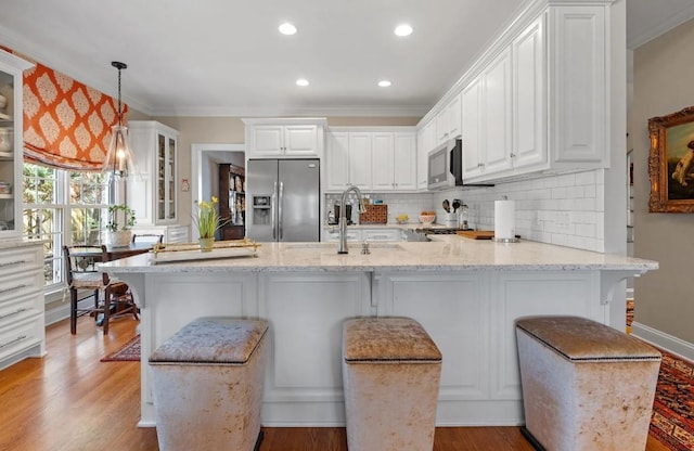 kitchen with stainless steel appliances, white cabinetry, pendant lighting, and a kitchen bar