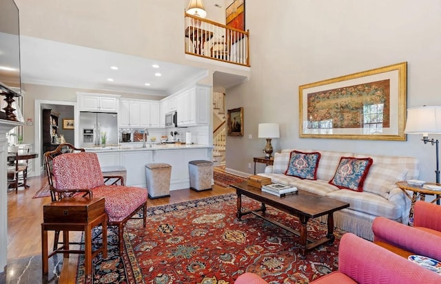 living room with hardwood / wood-style floors, crown molding, and a towering ceiling