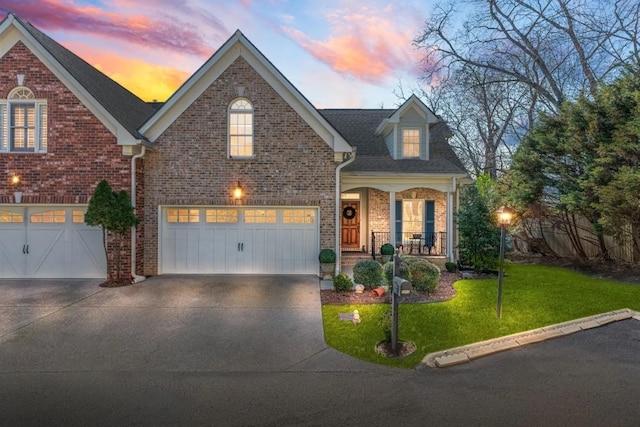 view of front of property featuring a garage, covered porch, and a lawn