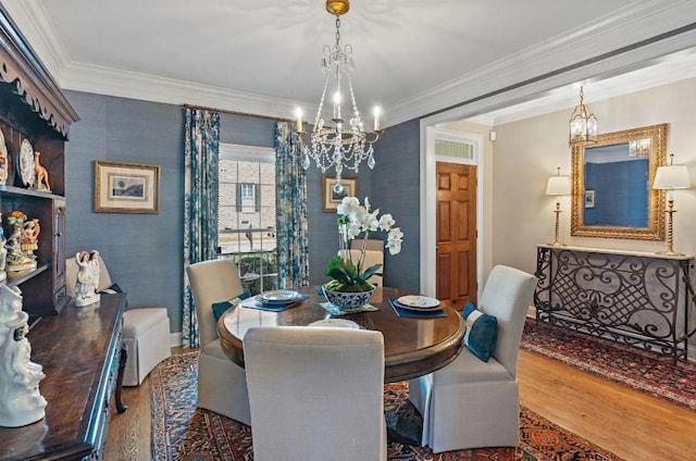 dining space with crown molding, hardwood / wood-style flooring, and a chandelier