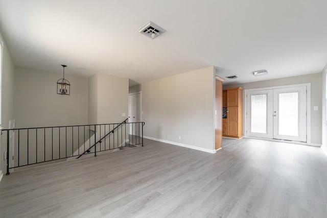 interior space featuring an inviting chandelier, french doors, and light wood-type flooring