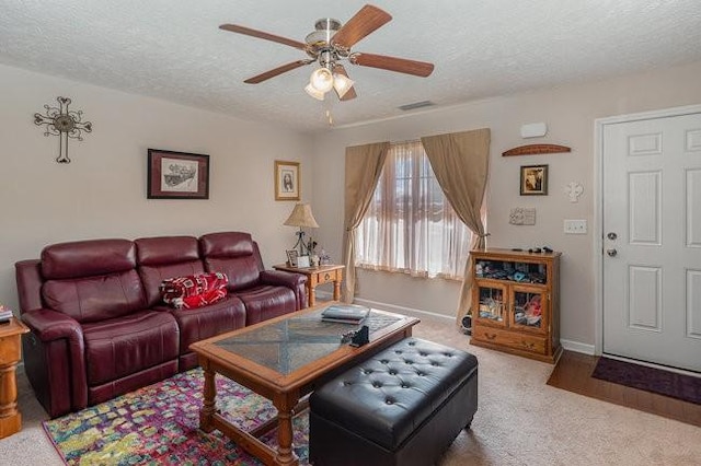 living room featuring ceiling fan, light carpet, and a textured ceiling