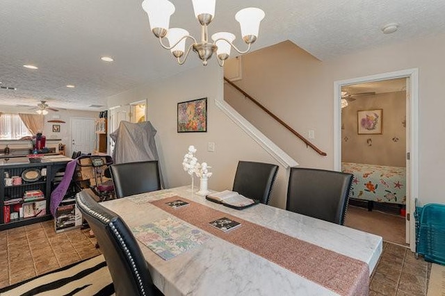 dining room featuring ceiling fan with notable chandelier, dark tile patterned floors, and a textured ceiling