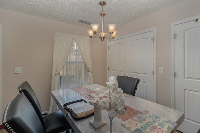 dining room with a chandelier and a textured ceiling