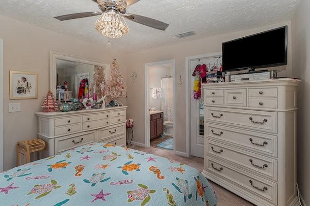 bedroom with light colored carpet, a textured ceiling, ceiling fan, and ensuite bath