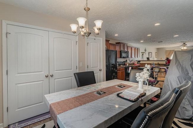 dining area featuring ceiling fan with notable chandelier and a textured ceiling