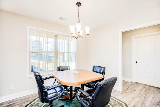 dining space featuring light wood-type flooring and a notable chandelier