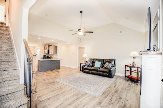 living room with vaulted ceiling, ceiling fan, and light wood-type flooring