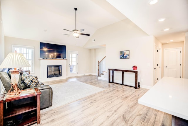 living room featuring lofted ceiling, light hardwood / wood-style flooring, and ceiling fan