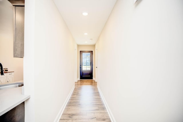 corridor with sink and light wood-type flooring