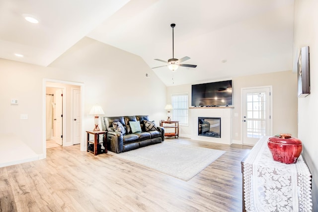 living room with ceiling fan, light hardwood / wood-style flooring, a healthy amount of sunlight, and vaulted ceiling