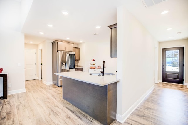 kitchen featuring stainless steel fridge, sink, and light wood-type flooring