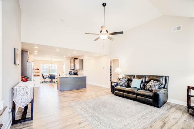 living room featuring ceiling fan, high vaulted ceiling, and light hardwood / wood-style flooring