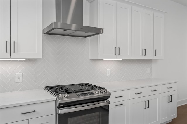 kitchen with decorative backsplash, stainless steel gas stove, white cabinets, and wall chimney exhaust hood