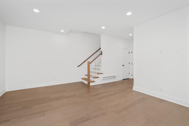 spare room featuring a baseboard heating unit and light hardwood / wood-style floors