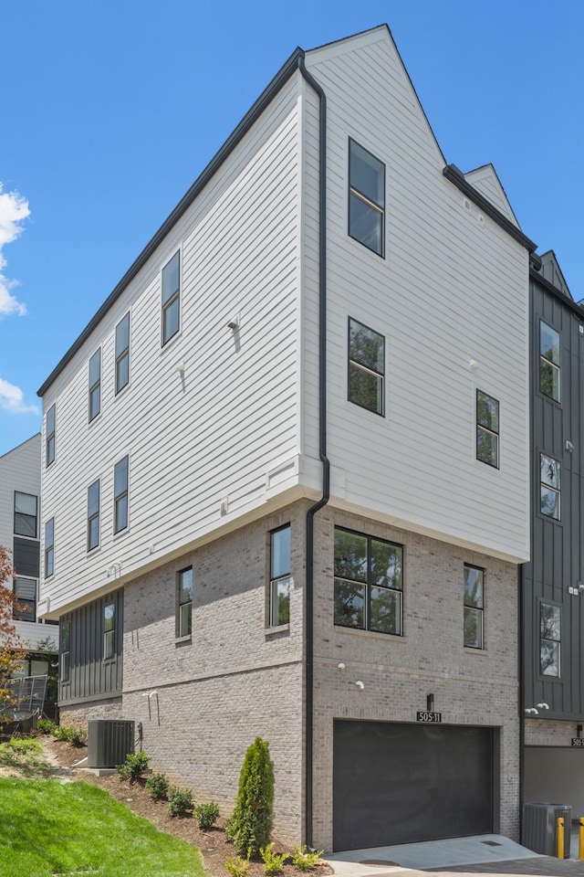 rear view of property featuring central AC and a garage