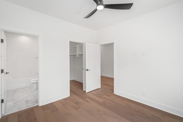 unfurnished bedroom with ceiling fan, connected bathroom, light hardwood / wood-style floors, a spacious closet, and a closet